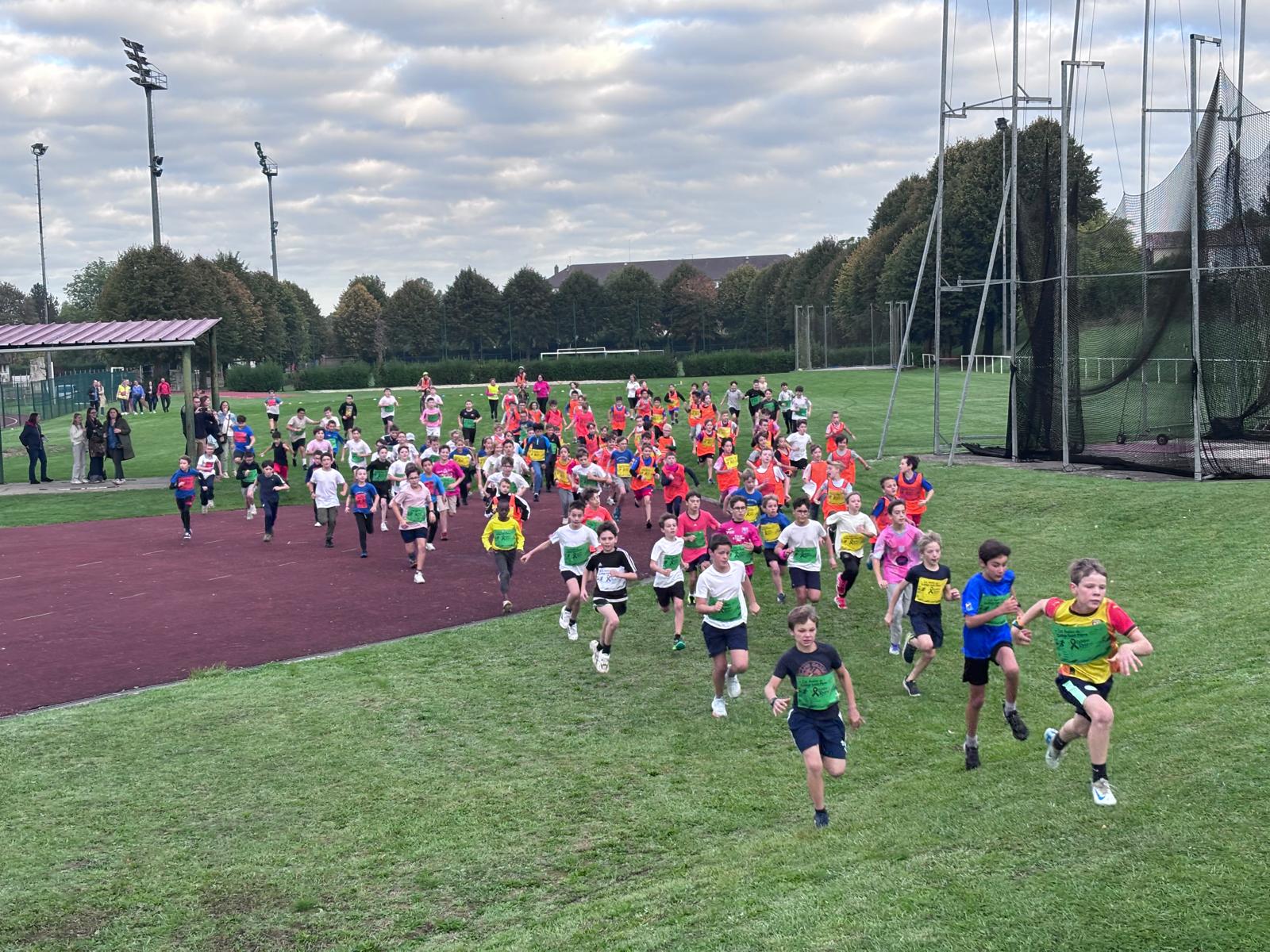Départ d'une course lors du cross « Les Foulées de St-Pierre » : des dizaines d'élèves courent sur la pelouse du stade Paul-Delique à Abbeville